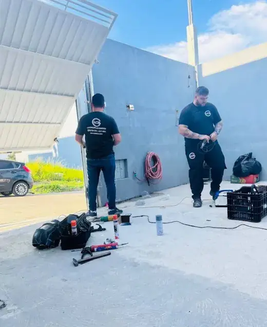 Dois técnicos da LCA com uniforme preto fazendo manutenção em um portão basculante